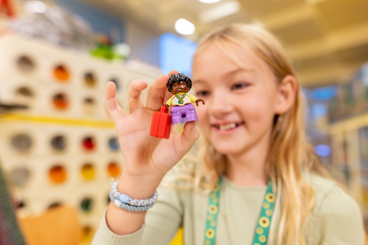 Une enfant qui tient un personnage LEGO dans un magasin