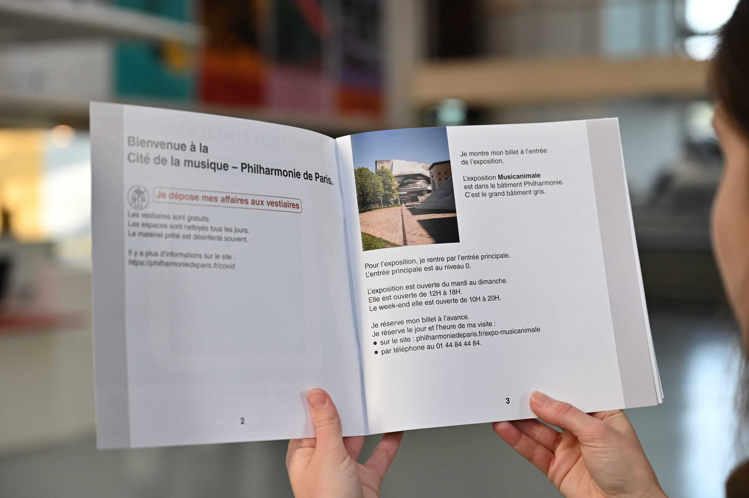 Une visiteuse de la Philharmonie de Paris tient un livret FALC ouvert dans ses mains