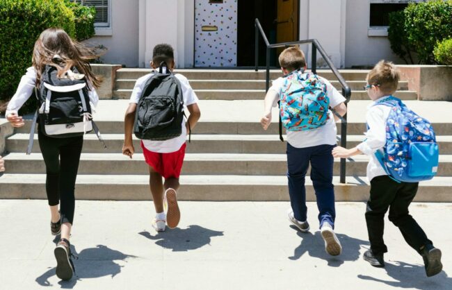 Des écoliers courent vers l'entrée leur école lors de la rentrée
