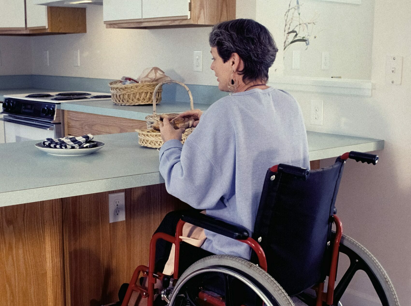 Une femme en fauteuil roulant dans sa cuisine