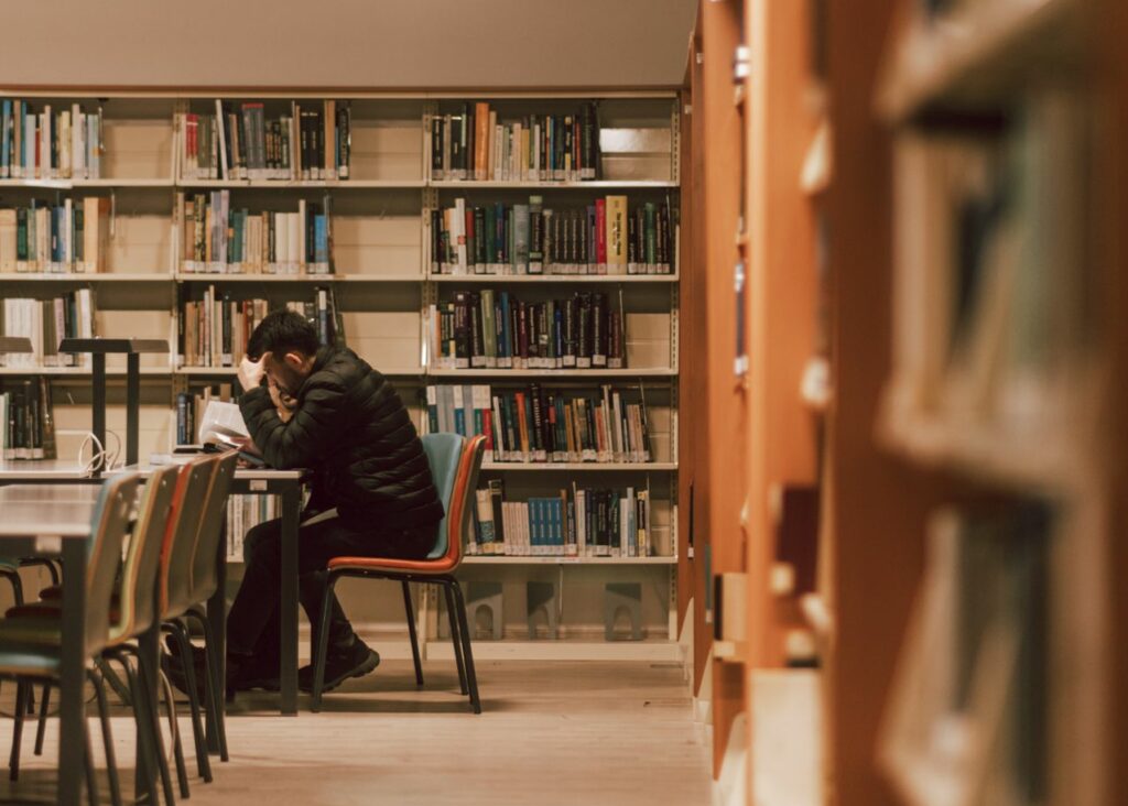 Un étudiant travaille sur son mémoire dans une bibliothèque