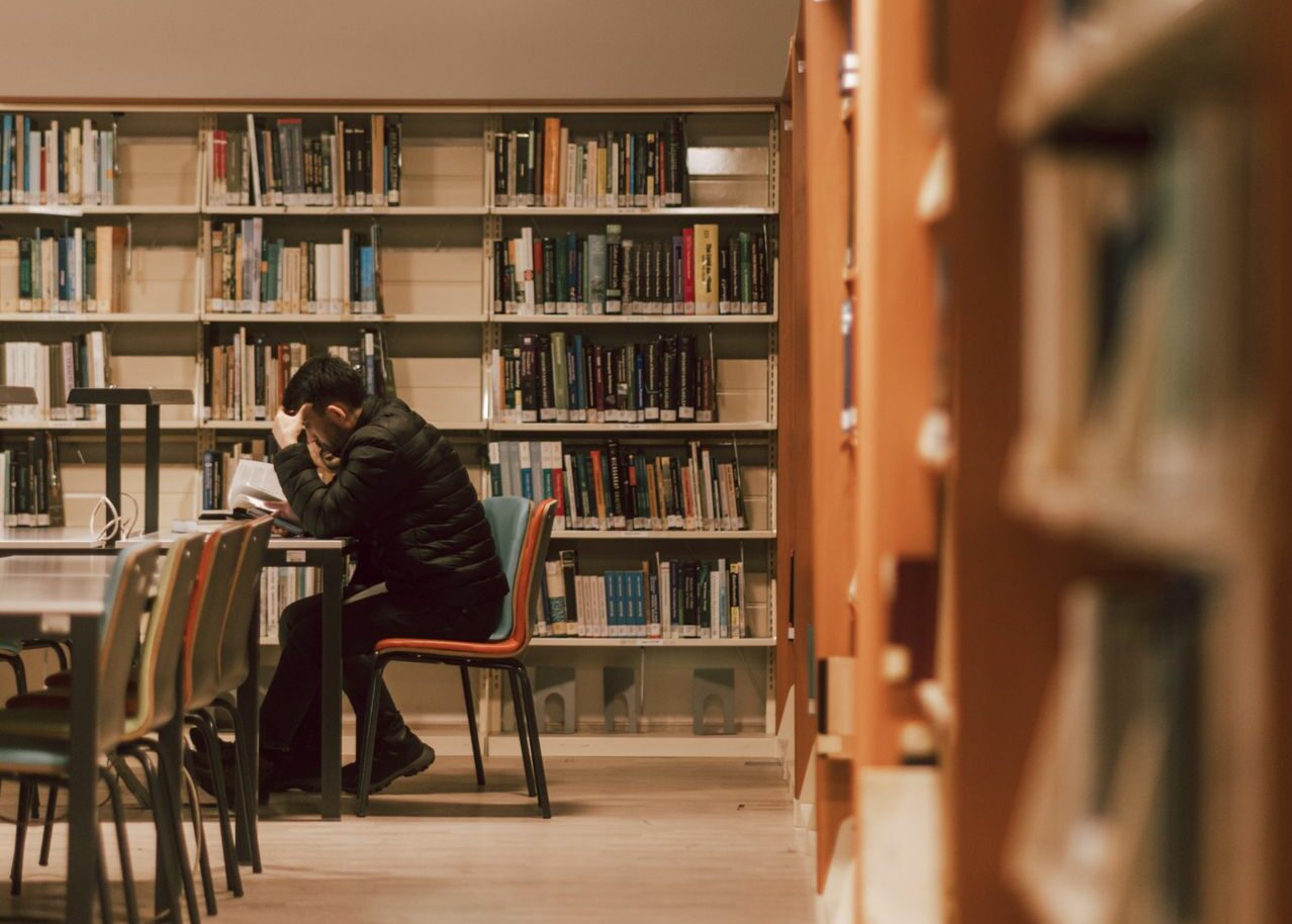 Un étudiant travaille sur son mémoire dans une bibliothèque