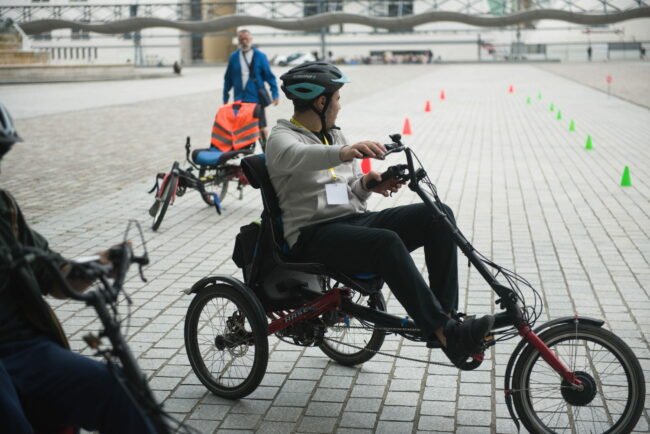 Un jeune en situation de handicap sur un tricycle au Parc de la Vilette