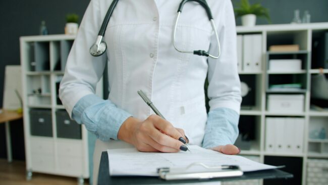 medecin-cabinet-medical Une médecin remplit un formulaire dans son cabinet médical