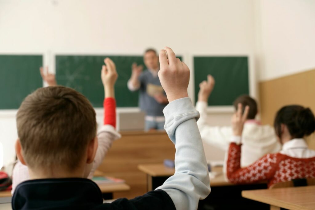 Des élèves dans une salle de classe levant les mains