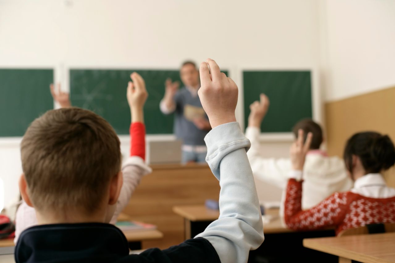 Des élèves dans une salle de classe levant les mains